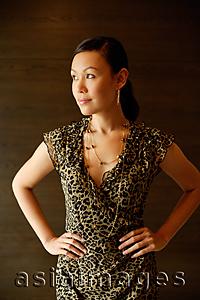 Asia Images Group - Woman in animal print dress, hands on hips, looking away