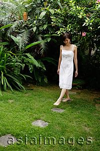 Asia Images Group - Woman in white dress stepping on stones in garden