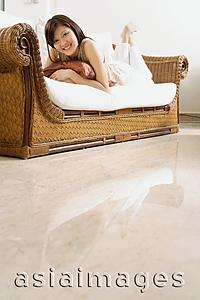 Asia Images Group - Woman lying on sofa smiling at camera