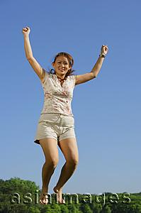 Asia Images Group - Woman jumping in mid air, smiling at camera