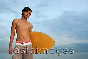 Asia Images Group - Young man with skimboard, looking at camera