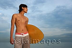 Asia Images Group - Young man with skimboard, looking away