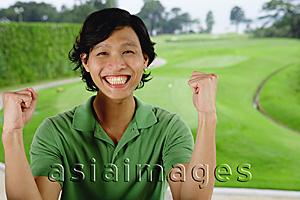 Asia Images Group - Man in green polo shirt, smiling at camera, hands raised as fists