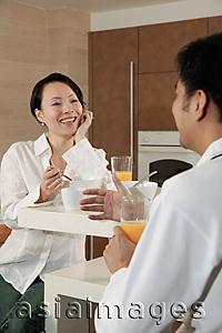 Asia Images Group - Man and woman sitting in kitchen, having breakfast