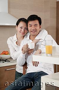 Asia Images Group - Couple in kitchen, woman with arm around man's shoulder, smiling at camera