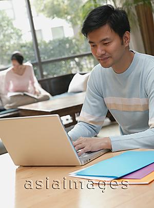 Asia Images Group - Couple at home, man using laptop, woman in background