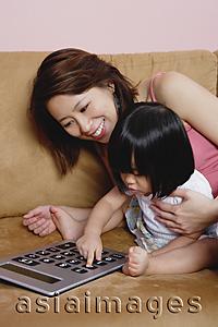Asia Images Group - Mother with young daughter, using calculator