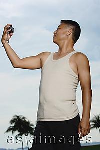 Asia Images Group - Mature adult in tank top, holding camera, taking pictures of himself