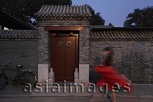 Asia Images Group - Woman walking in front of  Hutong, Beijing, China