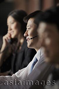 Asia Images Group - Closeup of man with headset on, people in background