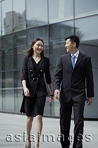 Asia Images Group - Young man and woman wearing suits walking in front of a building