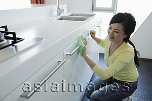 Asia Images Group - Young woman cleaning a kitchen and smiling