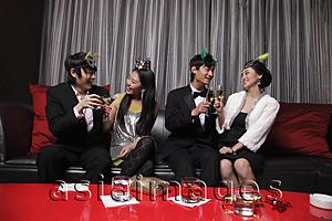 Asia Images Group - Four people dressed up at a party, toasting each other