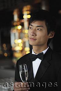 Asia Images Group - Head shot of young man wearing a tuxedo and holding a glass of champagne
