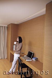 Asia Images Group - Young woman leaning next to desk holding coffee