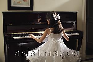 Asia Images Group - Rear view of young girl playing piano in white dress
