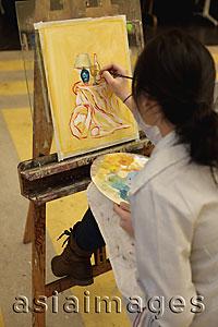 Asia Images Group - Rear view of young woman painting on an easel.