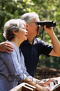 AsiaPix - Senior couple side by side, man using binoculars