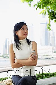 AsiaPix - Young woman, holding mobile phone, arms crossed