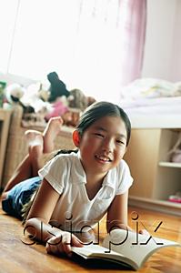 AsiaPix - Girl in bedroom, lying on floor, with book, looking at camera