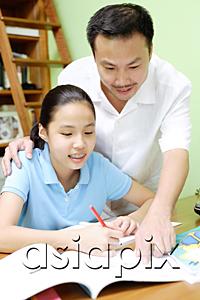 AsiaPix - Girl doing homework, father standing next to her, pointing at book