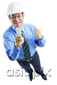 AsiaPix - Man wearing hardhat looking at mobile phone, making a fist