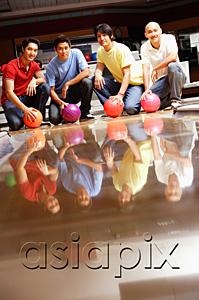 AsiaPix - Four men in bowling alley, crouching, holding bowling balls