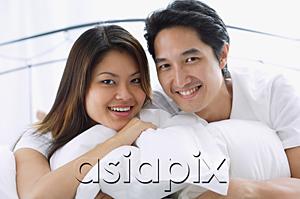 AsiaPix - Couple on bed, hugging pillows, smiling at camera, portrait