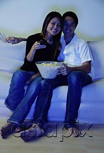 AsiaPix - Couple sitting on sofa, watching TV, woman holding remote control