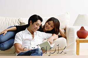 AsiaPix - Woman lying on sofa, man sitting on floor in front of her, looking at book