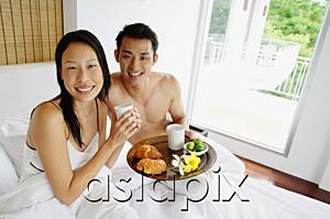 AsiaPix - Couple having breakfast in bed, looking at camera