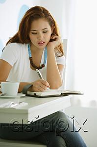 AsiaPix - One woman sitting at table, writing