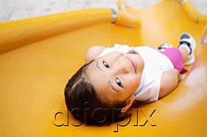 AsiaPix - Girl lying on slide, smiling at camera
