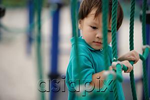 AsiaPix - Young boy in playground, holding on to rope net