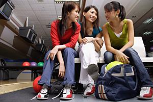 AsiaPix - Women sitting side by side in bowling alley