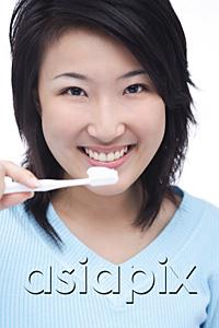 AsiaPix - Young woman brushing teeth, smiling at camera