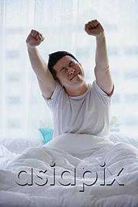AsiaPix - Man sitting in bed, stretching