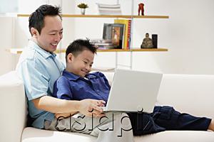 AsiaPix - Father and son in living room, looking at laptop
