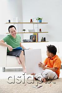AsiaPix - Father sitting on sofa, son on floor holding up drawing pad
