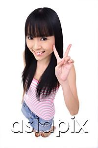 AsiaPix - Young woman making peace sign, smiling up at camera