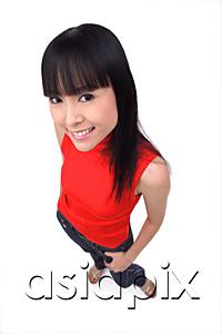 AsiaPix - Young woman looking at camera, hands in pockets, smiling