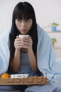 AsiaPix - Young woman on bed with cup of coffee