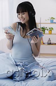 AsiaPix - Young woman listening to music and looking at CDs
