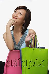 AsiaPix - Young woman with shopping bags, looking away, hand on chin