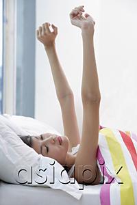 AsiaPix - Young woman lying on bed, hands outstretched