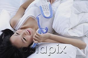 AsiaPix - Young woman on bed, using telephone
