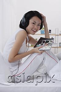 AsiaPix - Young woman listening to music, smiling