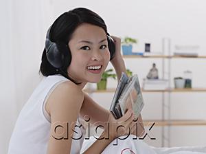 AsiaPix - Young woman listening to music, smiling, head shot