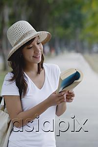 AsiaPix - Young woman wearing hat, reading a book