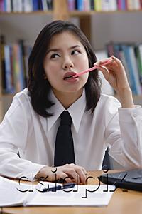 AsiaPix - Young woman in library, biting pen, looking way